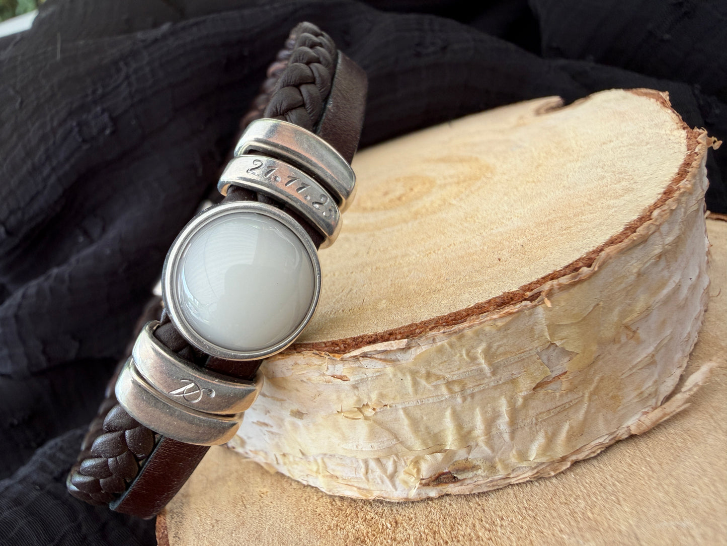 Bracelet en cuir brun contenant une pierre de lait maternel et la gravure de l'initial et la date de naissance de bébé.