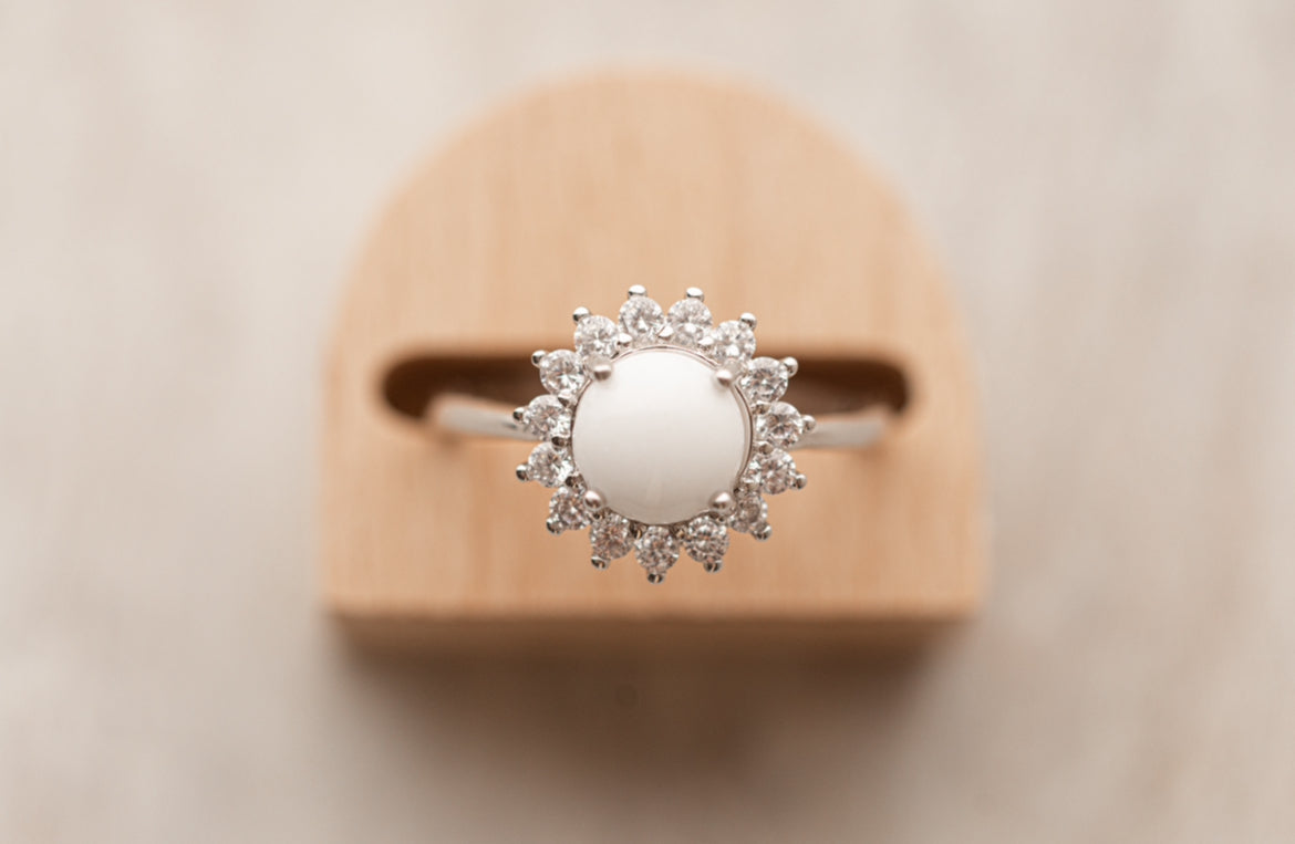 Bague souvenir avec un superbe cabochon de lait maternel et mèche de cheveux de bébé, entourée de strass étincellantes. 