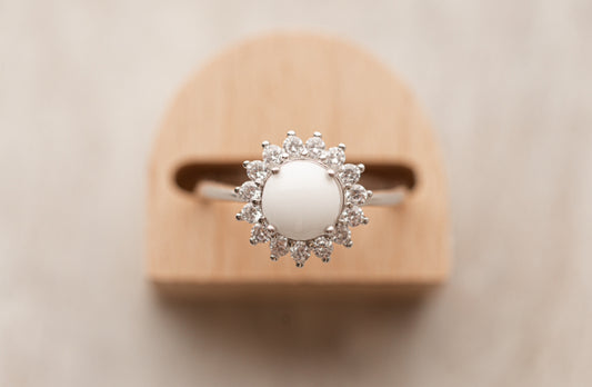 Bague souvenir avec un superbe cabochon de lait maternel et mèche de cheveux de bébé, entourée de strass étincellantes. 