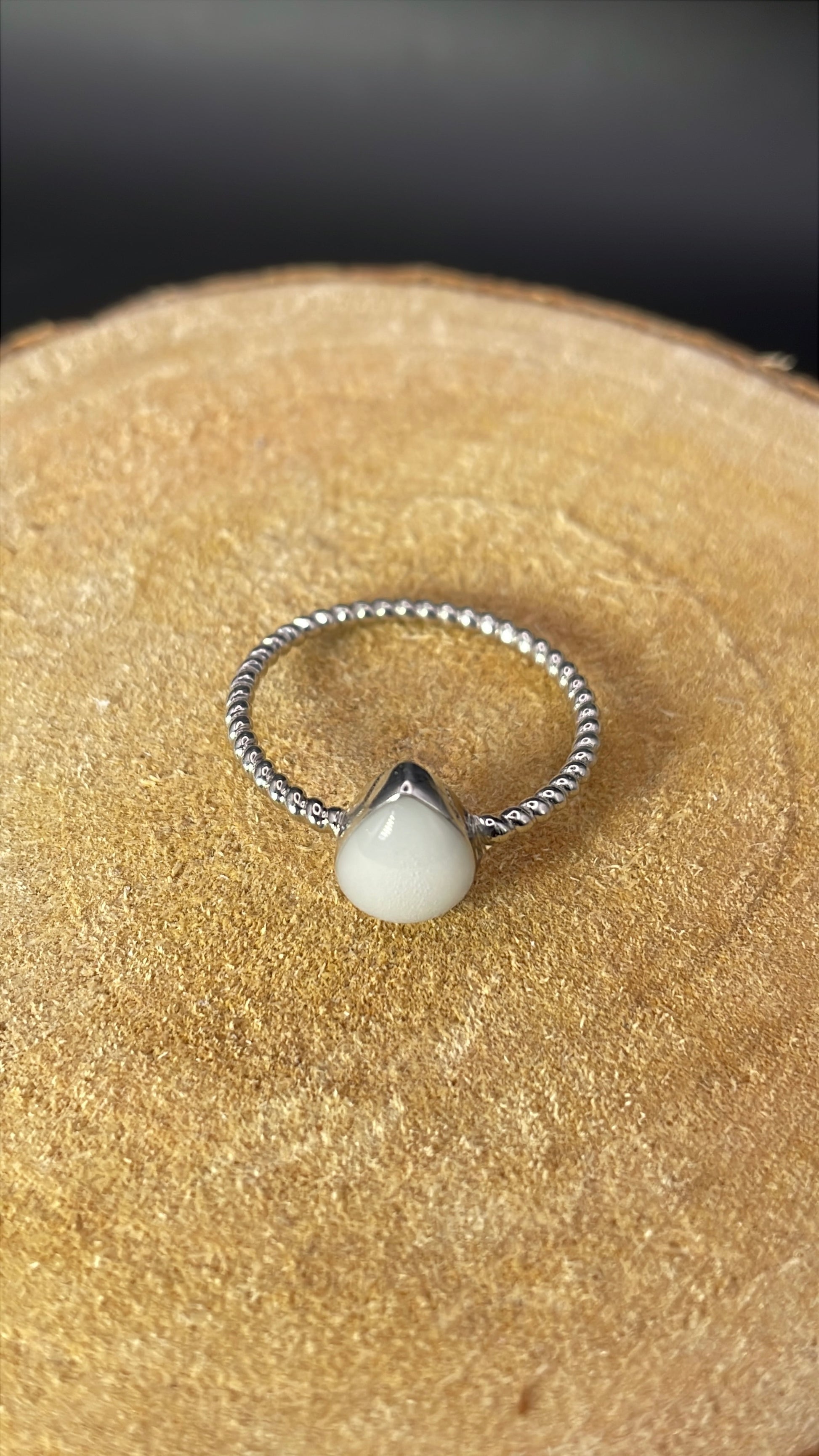 Bague représentant une goutte avec un corps de bague torsadé et délicat. Elle contient le souvenir de votre choix, comme ici du lait maternel. 