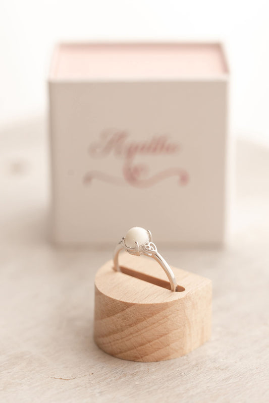 Bague en argent avec au centre un cabochon ovale de lait maternel entourée de 2 coeurs dans le corps de la bague