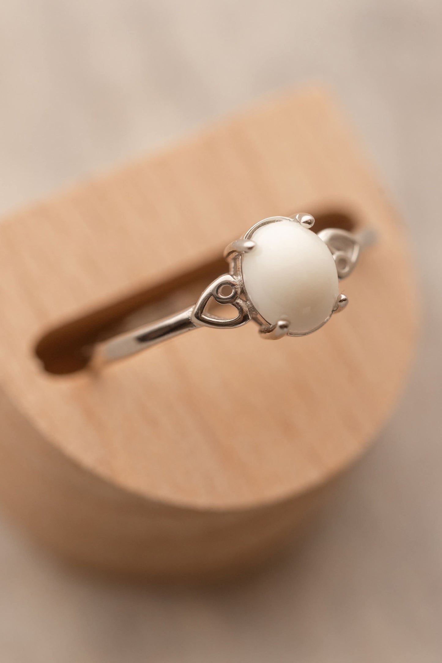 Bague en argent avec au centre un cabochon ovale de lait maternel entourée de 2 coeurs dans le corps de la bague