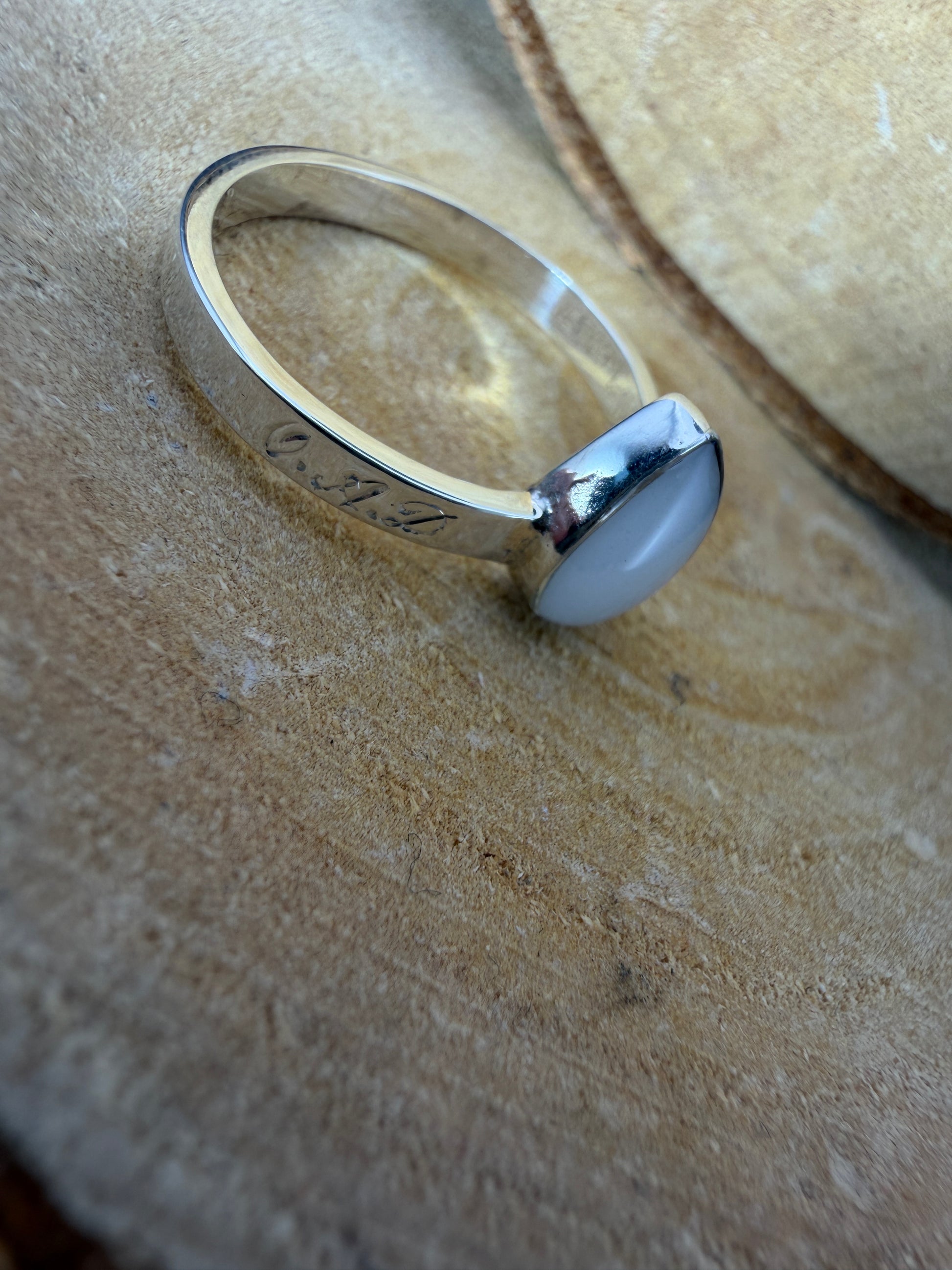 bague en forme de goutte avec mèche de cheveux de bébé, lait maternel et gravure des initiales sur l'extérieur de l'anneau