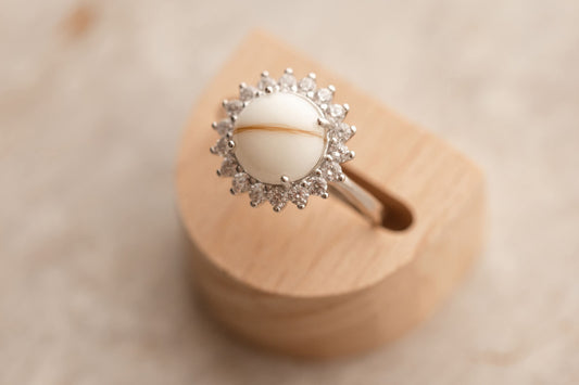 Bague souvenir avec un superbe cabochon de lait maternel et mèche de cheveux de bébé, entourée de strass étincellantes. 