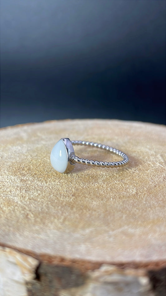 Bague représentant une goutte avec un corps de bague torsadé et délicat. Elle contient le souvenir de votre choix, comme ici du lait maternel. 